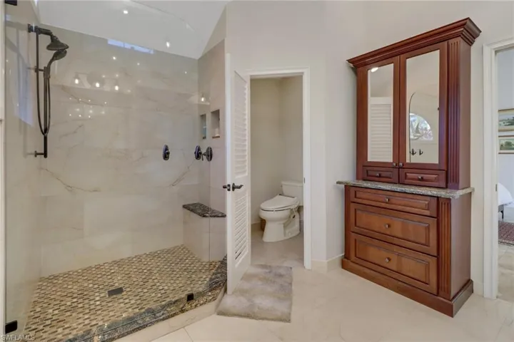 Full bathroom with a marble finish shower and toilet