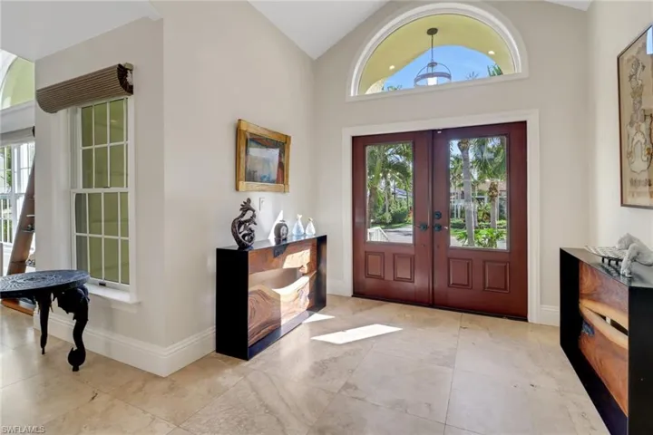 Entryway with french doors, light tile patterned flooring, and high vaulted ceiling