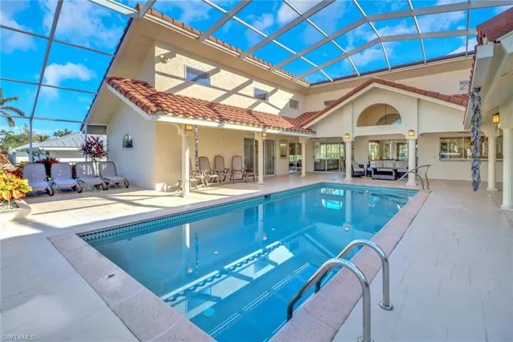 Rear view of house featuring an outdoor living space, a patio, stucco siding, glass enclosure, and an outdoor pool
