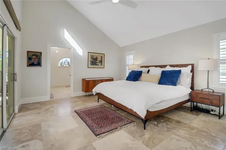Bedroom with high vaulted ceiling, ceiling fan, and access to outside