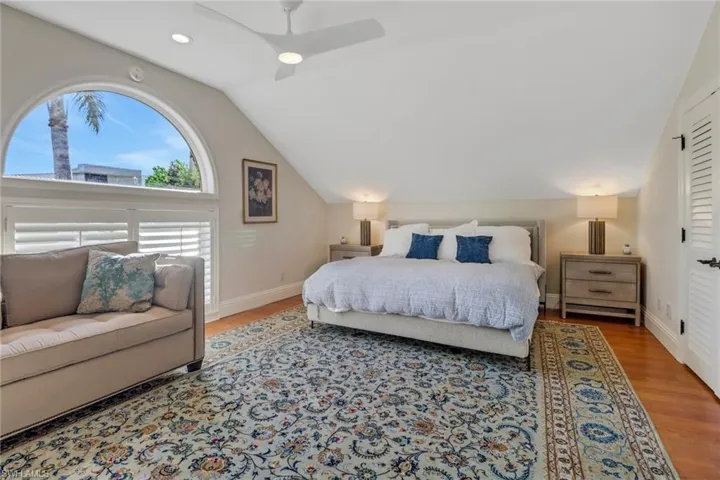 Bedroom with wood finished floors, vaulted ceiling, and a ceiling fan
