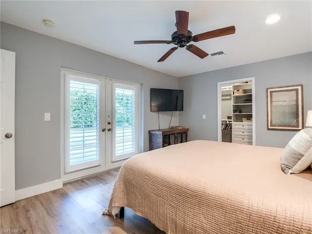 Bedroom with a walk in closet, light hardwood / wood-style flooring, access to exterior, a closet, and ceiling fan