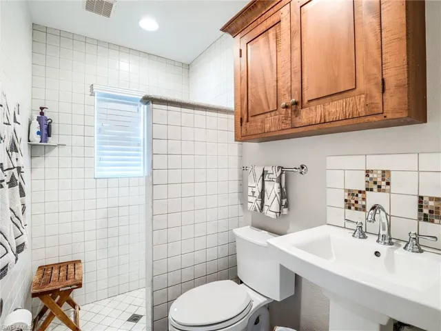 Bathroom with sink, tile walls, toilet, and a shower