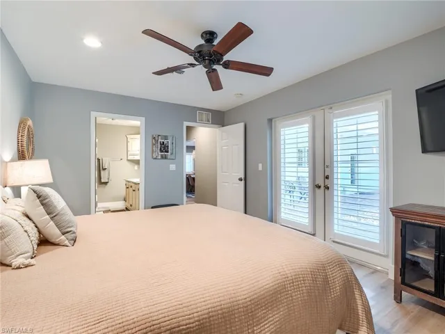 Bedroom with light hardwood / wood-style floors, french doors, access to outside, ensuite bath, and ceiling fan