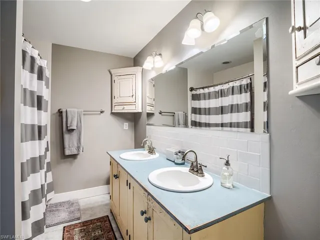 Bathroom with tile flooring, backsplash, double sink, and vanity with extensive cabinet space