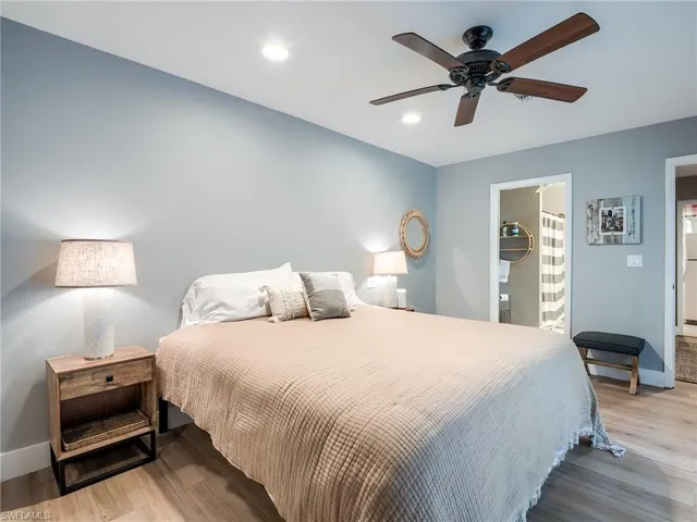 Bedroom with light hardwood / wood-style floors, ensuite bathroom, and ceiling fan