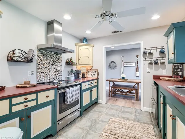 Kitchen with wooden counters, stainless steel range, wall chimney exhaust hood, and light hardwood / wood-style floors