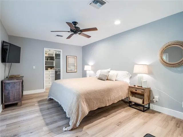 Master Bedroom with a spacious walk-in closet, tiled wood-style floors, and ceiling fan