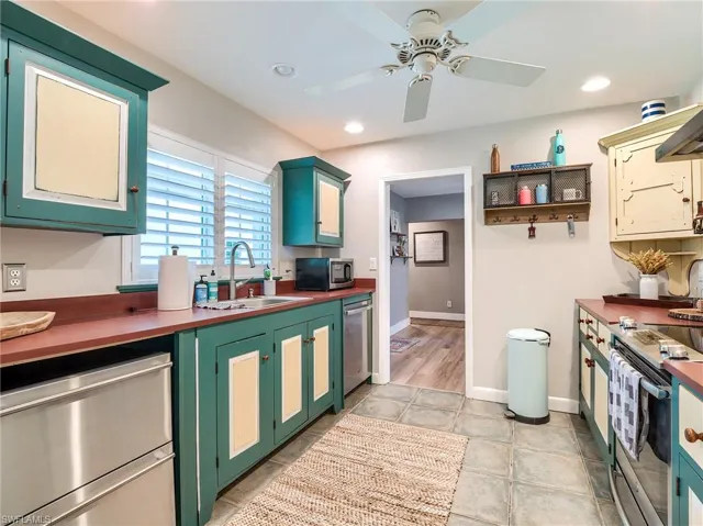 Kitchen with wood counters, light tile flooring, ceiling fan, appliances with stainless steel finishes, and sink