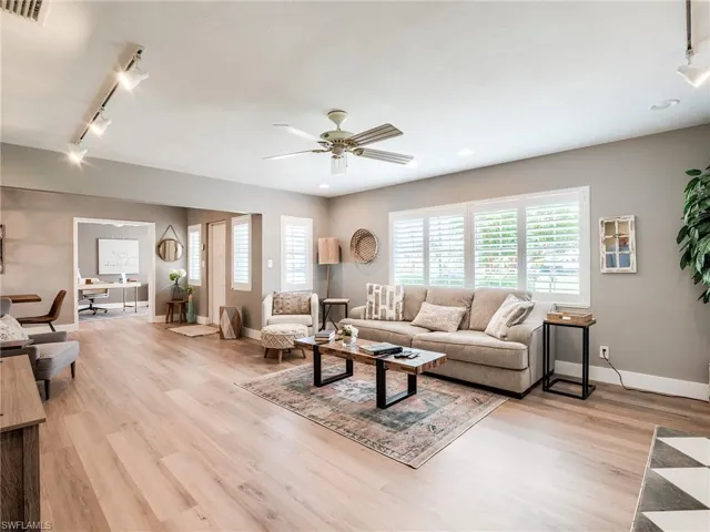 Living room with track lighting, ceiling fan, and light hardwood / wood-style floors