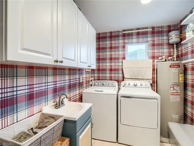 Clothes washing area with cabinets, sink, and electric water heater