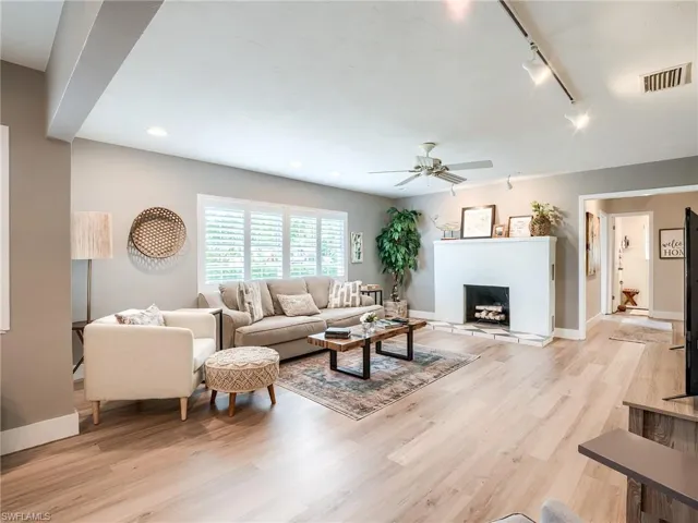 Living room with ceiling fan, light hardwood / wood-style flooring, and track lighting