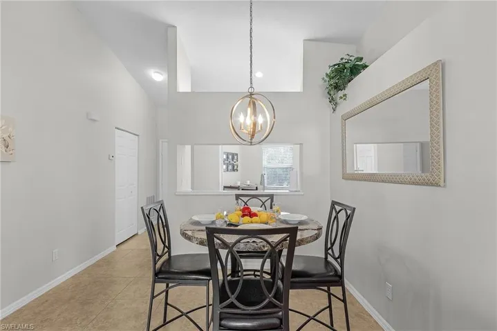 Dining room featuring light tile patterned flooring, a chandelier, recessed lighting, and high vaulted ceiling