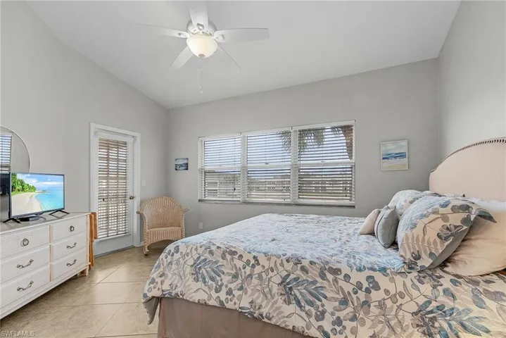 Bedroom featuring light tile patterned flooring, ceiling fan, lofted ceiling, and access to exterior