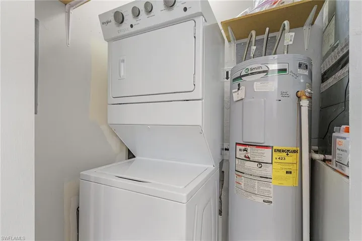 Laundry room featuring water heater and stacked washing machine and dryer