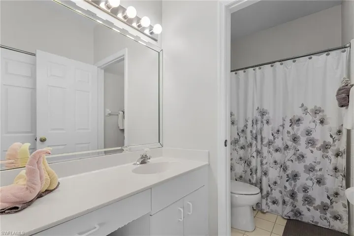Full bath with light tile patterned floors, vanity, and curtained shower