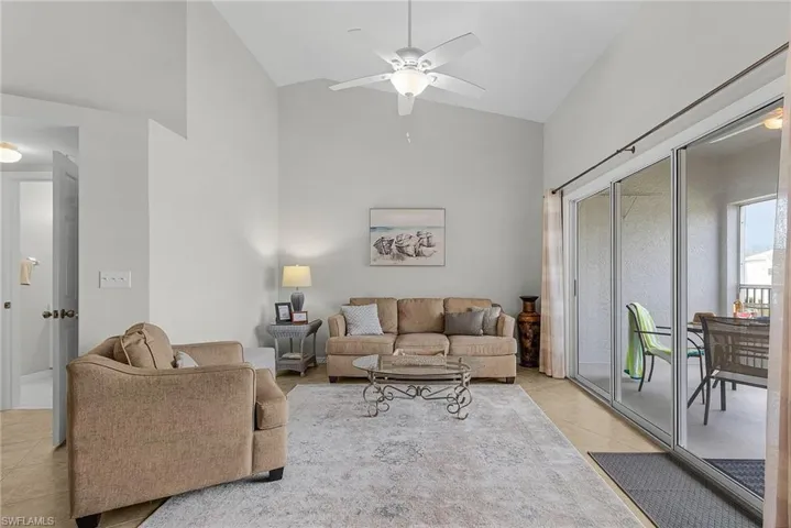 Living room featuring high vaulted ceiling, light tile patterned floors, and ceiling fan