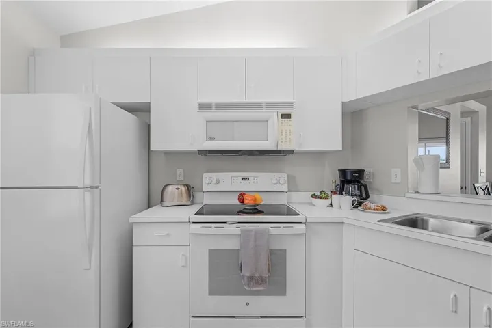 Kitchen featuring white appliances, light countertops, and white cabinets