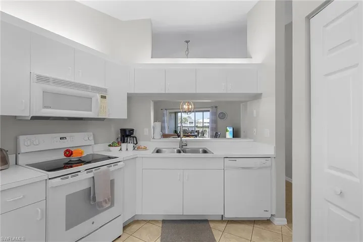 Kitchen with white appliances, light countertops, and white cabinets