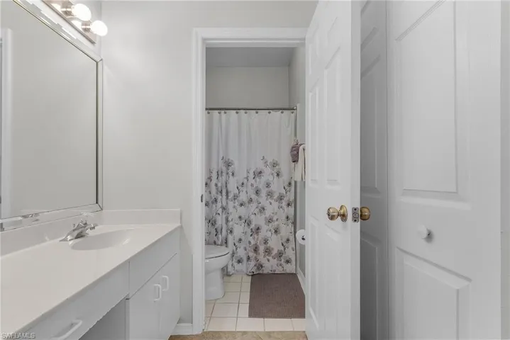 Full bathroom featuring light tile patterned floors, curtained shower, and vanity