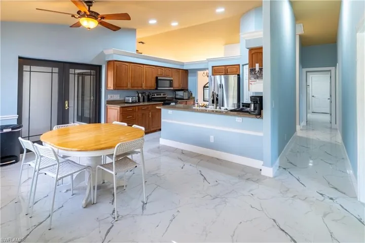 Kitchen featuring ceiling fan, appliances with stainless steel finishes, and high vaulted ceiling
