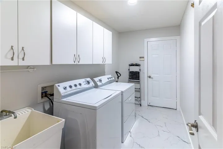 Washroom with cabinets, sink, and washer and clothes dryer