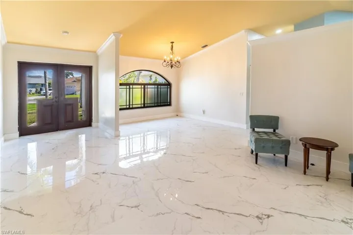 Entryway featuring ornamental molding, a chandelier, and french doors