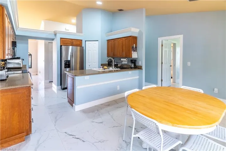 Kitchen with stainless steel refrigerator with ice dispenser, sink, and a high ceiling