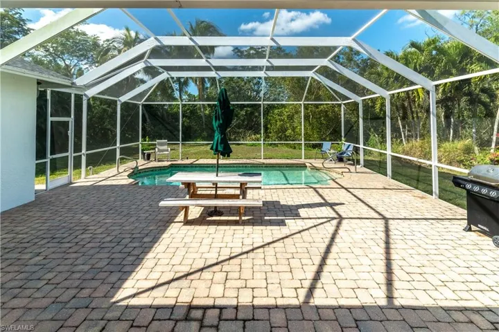 View of pool with area for grilling, a patio, glass enclosure, and a lawn