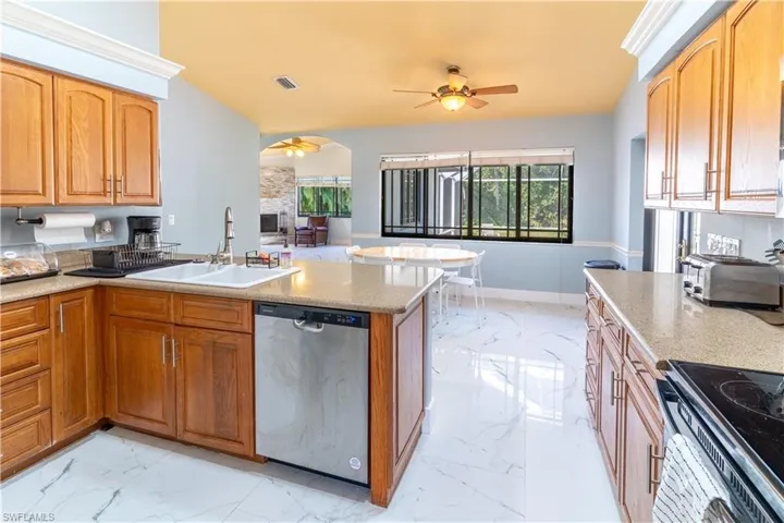 Kitchen featuring sink, ceiling fan, electric range oven, light stone countertops, and stainless steel dishwasher
