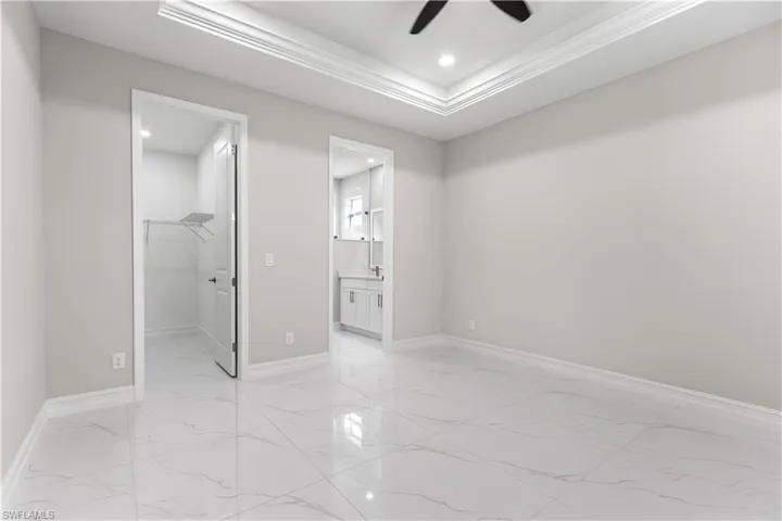 Bedroom featuring a closet, light tile flooring, ceiling fan, a walk in closet, and connected bathroom