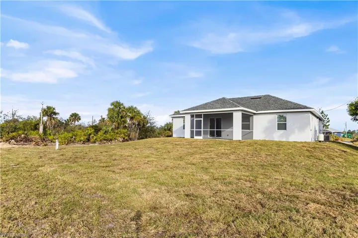 Back of property with a sunroom and a lawn