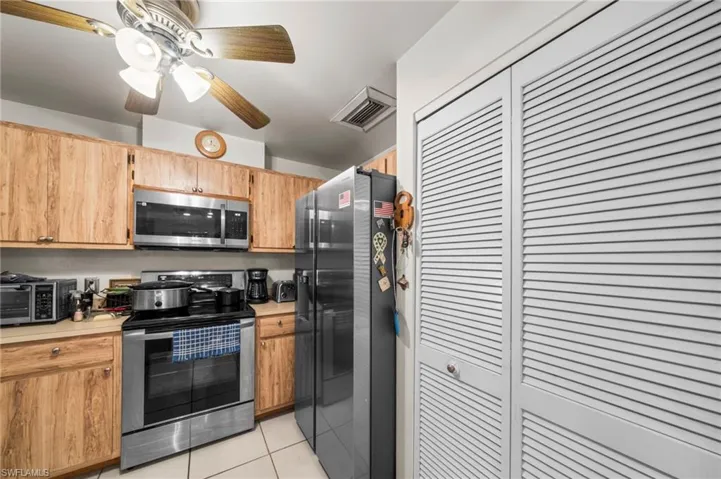 Kitchen with appliances with stainless steel finishes, light countertops, light tile patterned floors, and ceiling fan