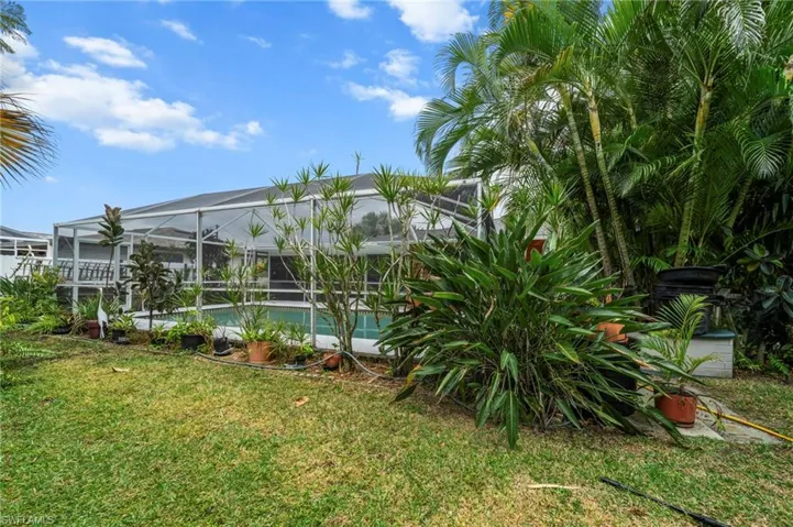 View of grassy yard featuring a sunroom, a lanai, and an outdoor pool