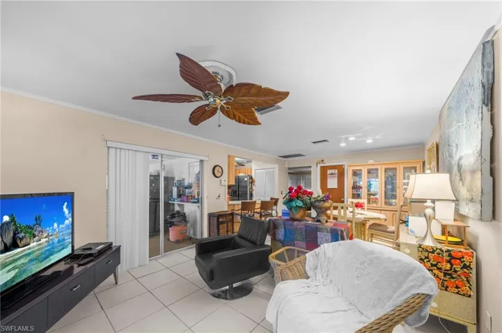 Living room featuring crown molding, light tile patterned flooring, and a ceiling fan