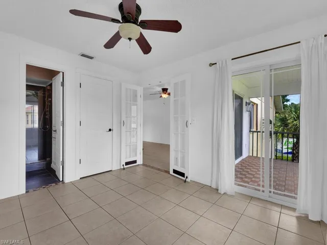 Unfurnished bedroom featuring multiple windows, access to exterior, light tile patterned floors, and ceiling fan