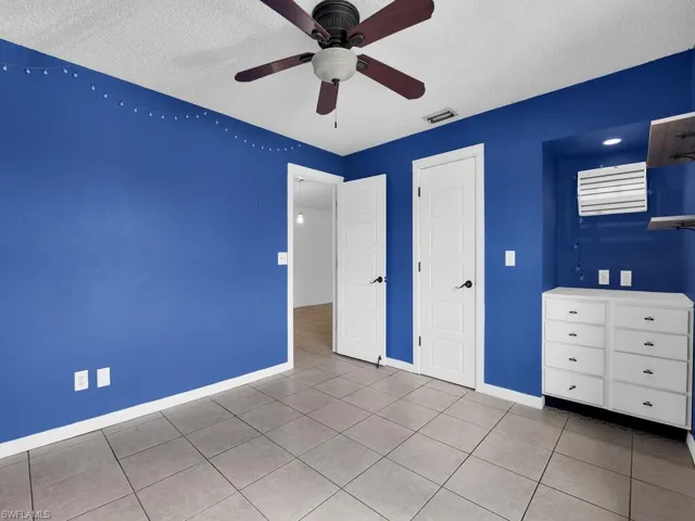 Unfurnished bedroom with a textured ceiling, ceiling fan, and light tile patterned floors