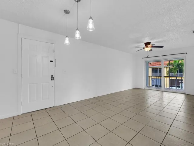 Unfurnished room with a textured ceiling, light tile patterned floors, and ceiling fan