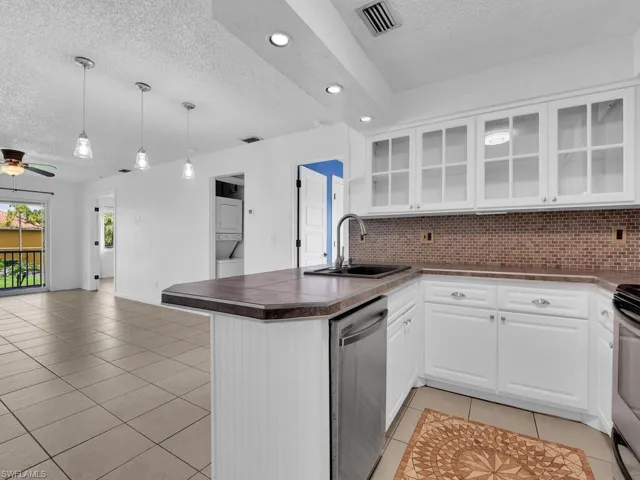 Kitchen with stacked washer / dryer, tasteful backsplash, ceiling fan, stainless steel appliances, and sink