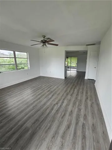 Empty room with dark wood-type flooring and a ceiling fan
