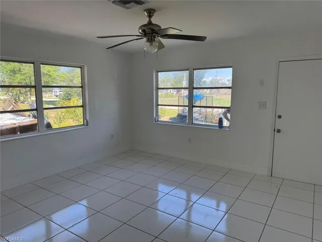 Empty room with light tile patterned floors and ceiling fan