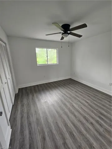 Unfurnished bedroom featuring dark wood-style floors, a closet, and a ceiling fan