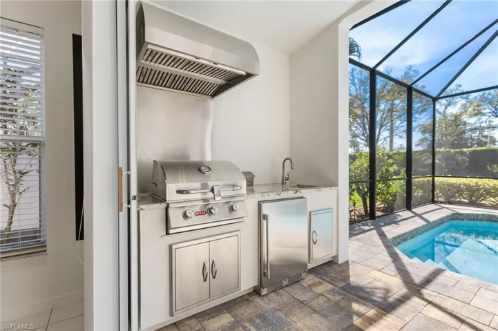 Outdoor kitchen offers a refrigerator, sink and a BULL grill.