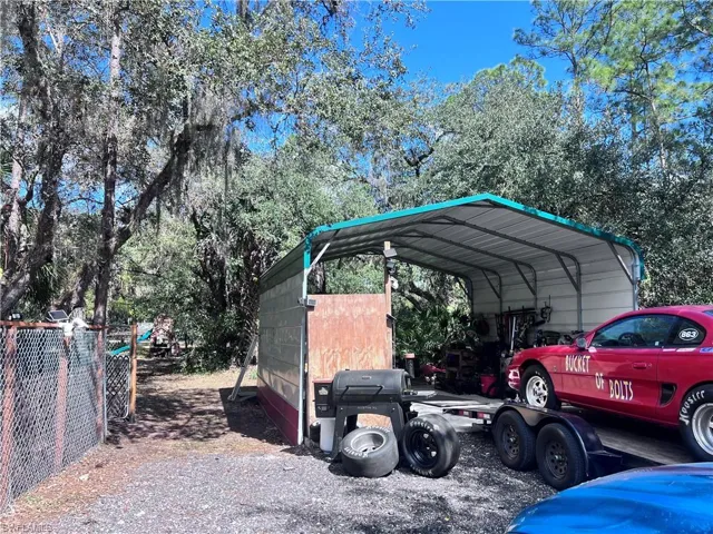 View of parking with a carport and view of scattered trees