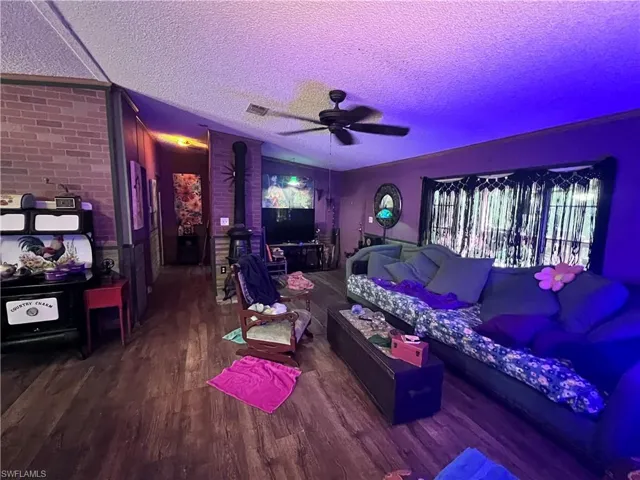 Living room featuring a textured ceiling, wood finished floors, and ceiling fan