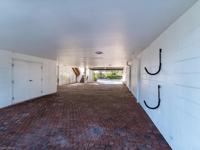 Hallway with concrete block wall, stairs, and brick floors