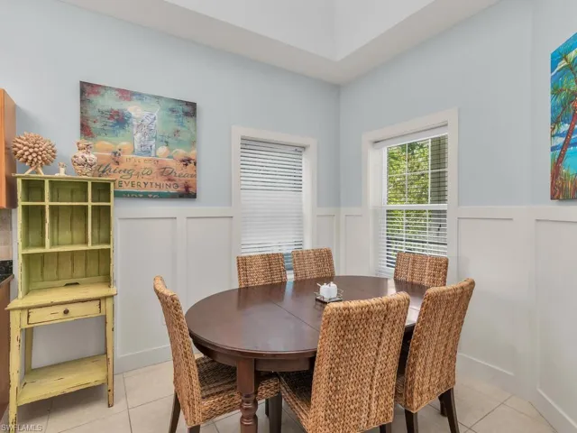 Dining room with a decorative wall, wainscoting, and light tile patterned floors