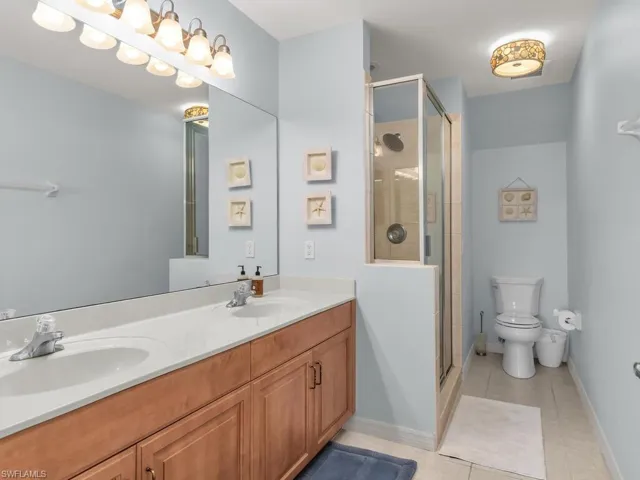 Bathroom featuring double vanity, a shower stall, and light tile patterned floors