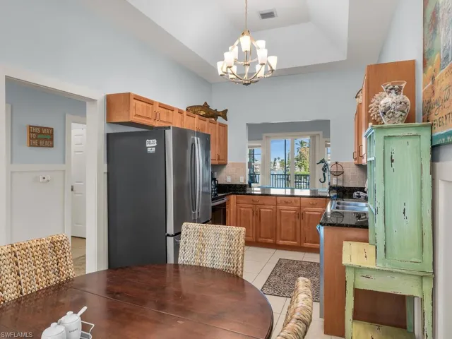 Kitchen with backsplash, freestanding refrigerator, brown cabinets, a raised ceiling, and dark stone counters