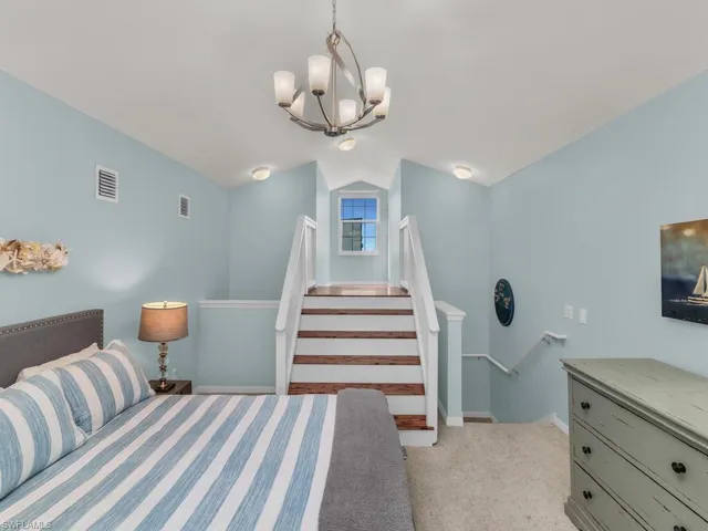 Bedroom featuring light colored carpet, lofted ceiling, and a chandelier